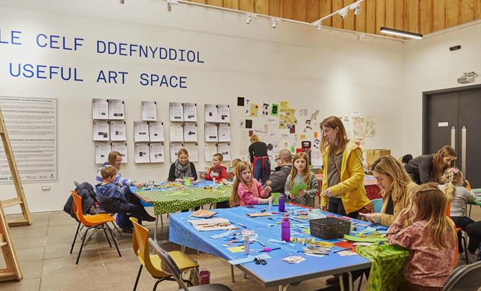 Tŷ Pawb's Useful Art Space, with children sat at tables taking part in craft activity